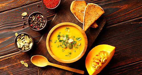 Image showing Pumpkin soup with bread on chopping board