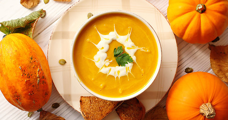 Image showing Creamy pumpkin soup in bowl with herb