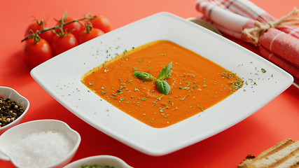 Image showing Tomato soup in plate with green leaf