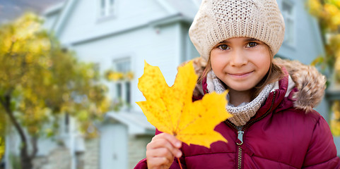 Image showing close up of girl with autumn maple leaf over house