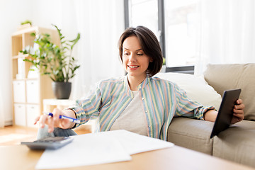 Image showing woman with tablet pc, bills and calculator at home