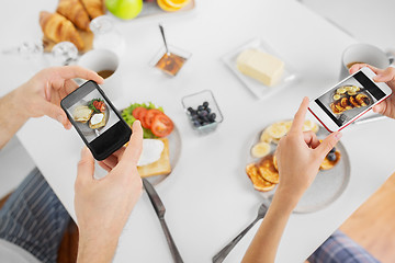 Image showing close up of couple with smartphones at breakfast