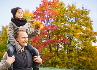 Image showing happy father carrying son with autumn maple leaves