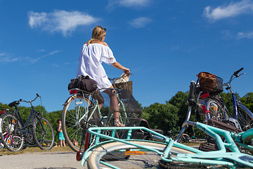 Image showing Young beautiful blonde woman enjoying a bycicle ride on a sunny summer day in urban city park.