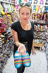 Image showing Female tourists looking at traditional arabic colorful leather shoes in shopping stall market in medina while traveling in Marrakesh, Morocco.