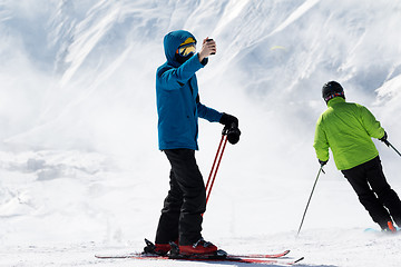 Image showing Skier makes selfie on camera phone and snow mountains in fog