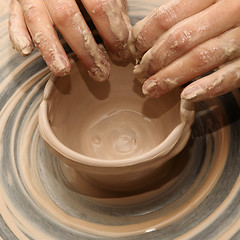 Image showing Woman in process of making clay bowl on pottery wheel