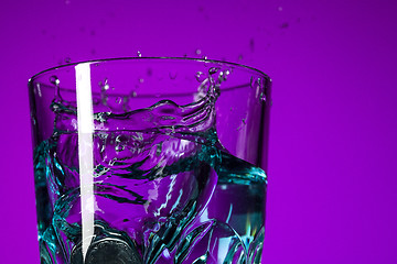 Image showing The water splashing in glass on lilac background