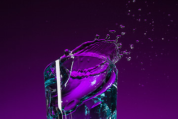 Image showing The water splashing in glass on lilac background