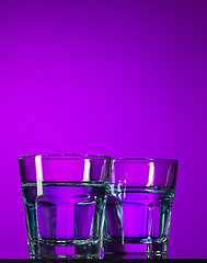 Image showing The water in two glassese on lilac background