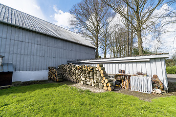 Image showing Barnyard with green grass and a woodstack