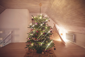 Image showing Christmas tree with glittering lights in a living room in the ho