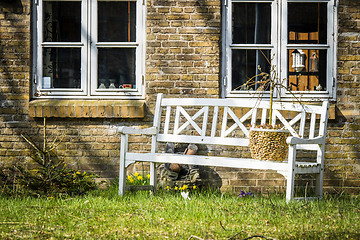 Image showing White bench outside an old brick house