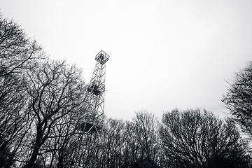 Image showing Small lighthouse tower in a forest with tree silhouettes