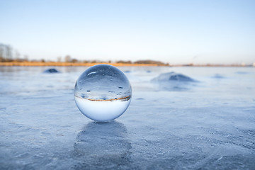 Image showing Transparent glass orb on a frozen lake with ice