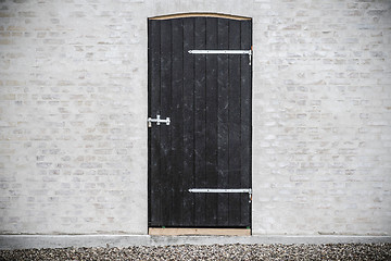 Image showing Black wooden door on a grey brick wall