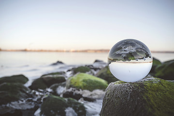 Image showing Glass orb on rocks by the sea