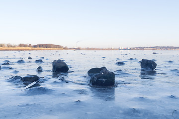 Image showing Black rocks in the ice on a frozen lake