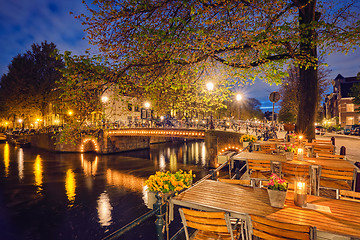 Image showing Amterdam cafe tables, canal, bridge and medieval houses in the e