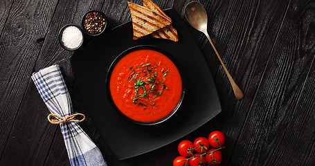 Image showing Tomato soup in black bowl with crisp bread 