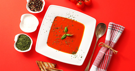 Image showing Tomato soup served in plate with spoon