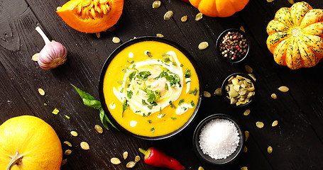 Image showing Yellow fresh pumpkin soup surrounded by spices and seeds