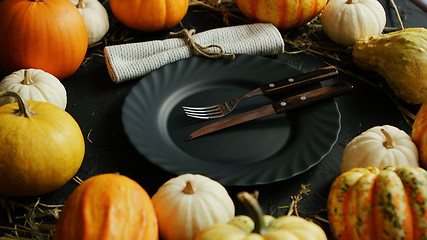 Image showing Black plate and cutlery surrounded by pumpkins