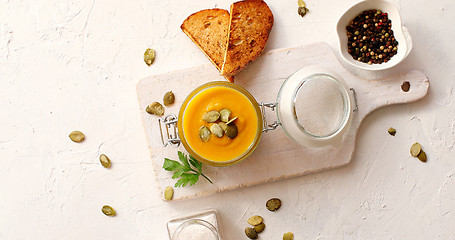 Image showing Pumpkin soup in glass jar on cutting board