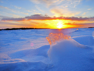 Image showing Transparent piece of ice on the snow against the backdrop of a winter sunset