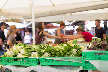 Image showing Blured unrecodnised people buying homegrown vegetable at farmers\' market stall with variety of organic vegetable.