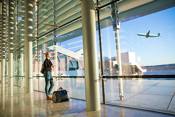 Image showing Young woman waiting at airport, looking through the gate window.