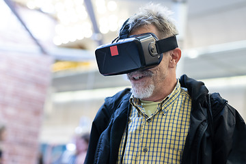 Image showing Senior man wearing virtual reality goggles watching virtual reality presentation.