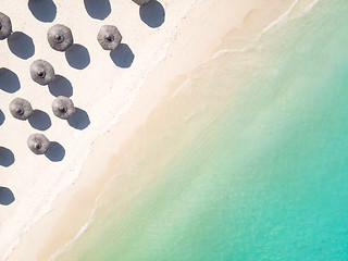 Image showing Aerial view of amazing tropical white sandy beach with palm leaves umbrellas and turquoise sea.