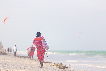 Image showing Rear view of traditonaly dressed maasai man selling hand made jewelry on picture perfect tropical Paje beach, Zanzibar, Tanzania, East Africa.