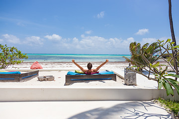 Image showing Relaxed man in luxury lounger, arms rised, enjoying summer vacations on beautiful beach.