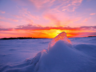 Image showing Transparent piece of ice on the snow against the backdrop of a winter sunset