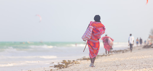 Image showing Rear view of traditonaly dressed maasai man selling hand made jewelry on picture perfect tropical Paje beach, Zanzibar, Tanzania, East Africa.