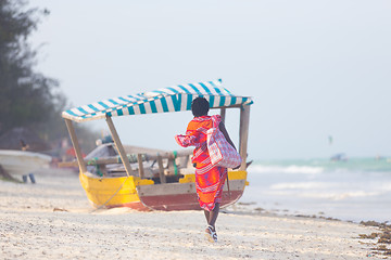 Image showing Rear view of traditonaly dressed maasai man selling hand made jewelry on picture perfect tropical Paje beach, Zanzibar, Tanzania, East Africa.