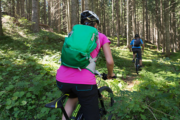 Image showing Active sporty couple riding mountain bikes on forest trail .