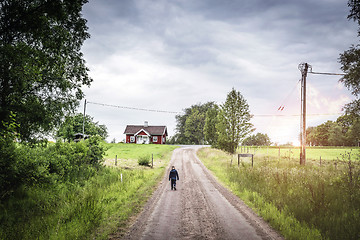 Image showing Young boy walking down a road in rural environment