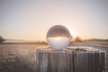 Image showing Glass orb on a wooden post in the sunrise