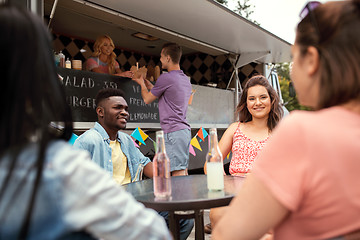 Image showing friends with drinks sitting at table at food truck