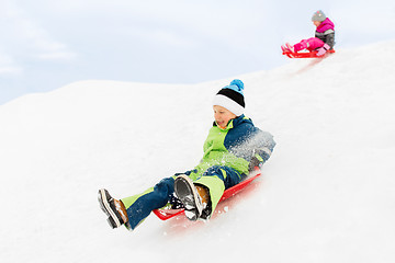 Image showing happy kids sliding on sleds down hill in winter