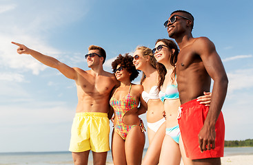 Image showing happy friends hugging on summer beach