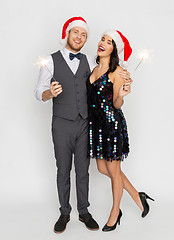 Image showing happy couple in santa hats at christmas party