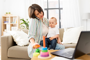 Image showing working mother with baby calling on smartphone