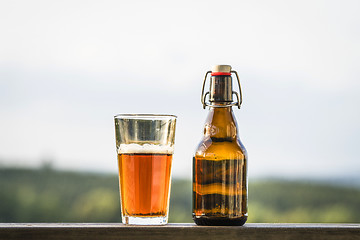 Image showing Glass of beer next to a bottle