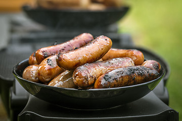 Image showing Grilled sausages on a plate at an outdoor barbecue