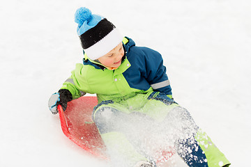 Image showing happy boy sliding on sled down snow hill in winter