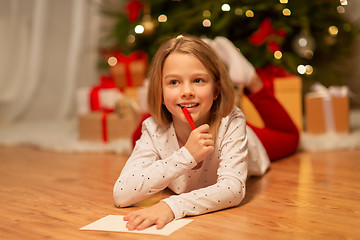 Image showing smiling girl writing christmas wish list at home